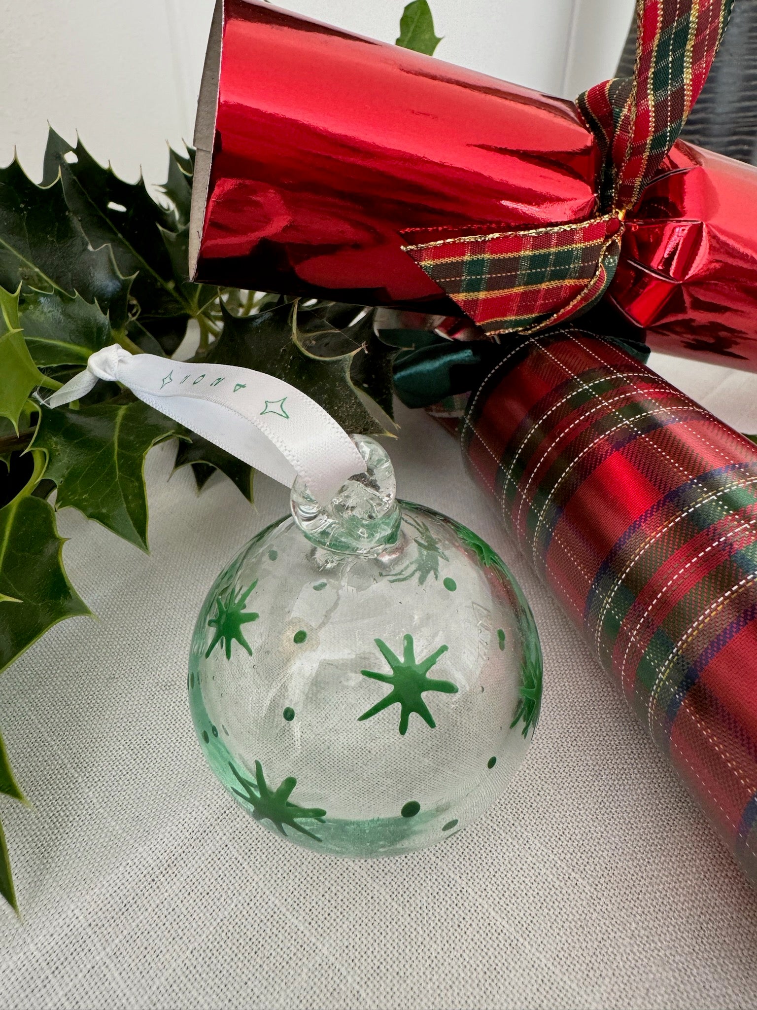 Clear recycled glass painted with green stars hanging on white ribbon. handmade in Bethlehem