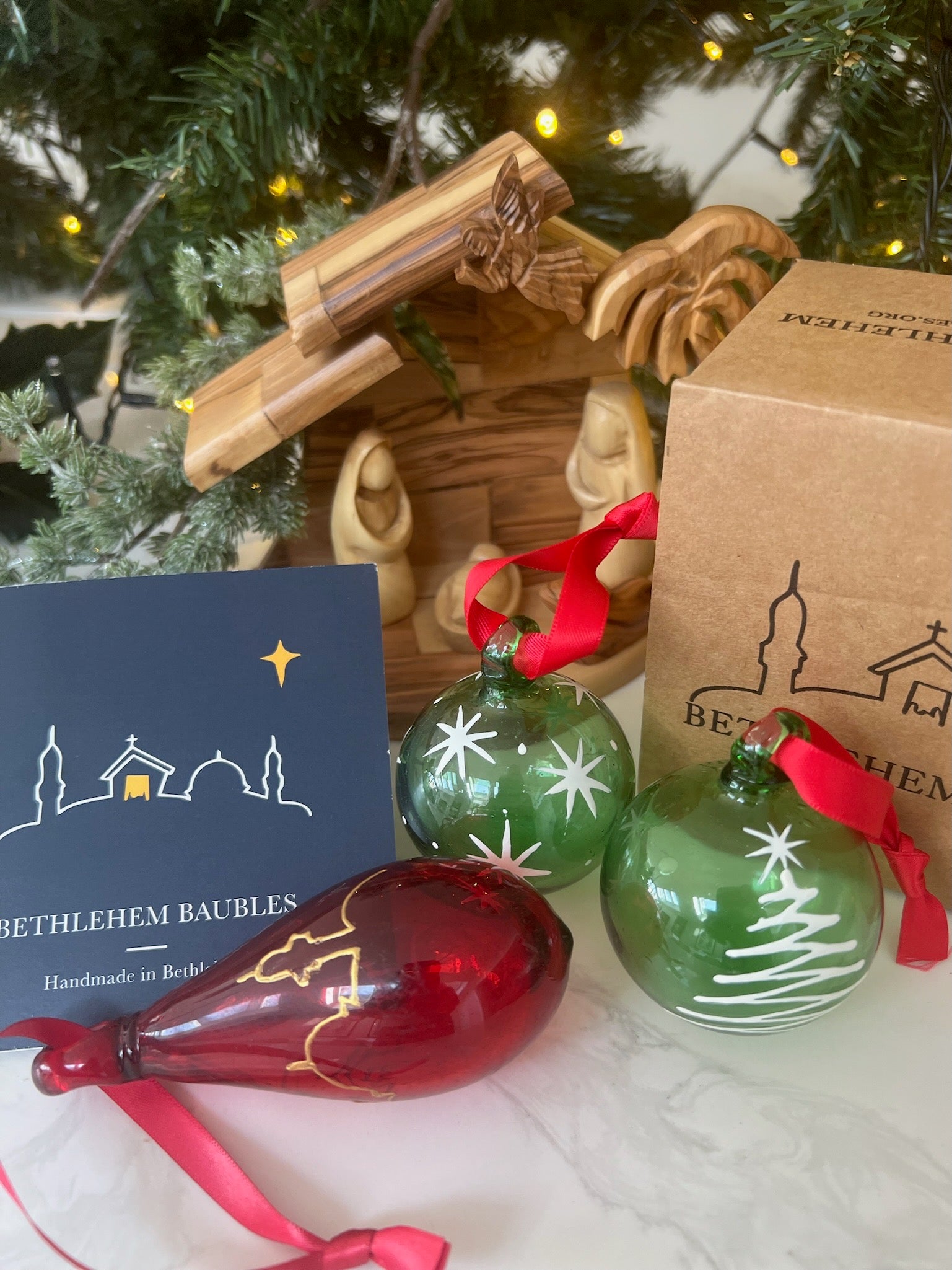 Red tear-shaped Christmas ornament with gold Bethlehem scene design, group view
